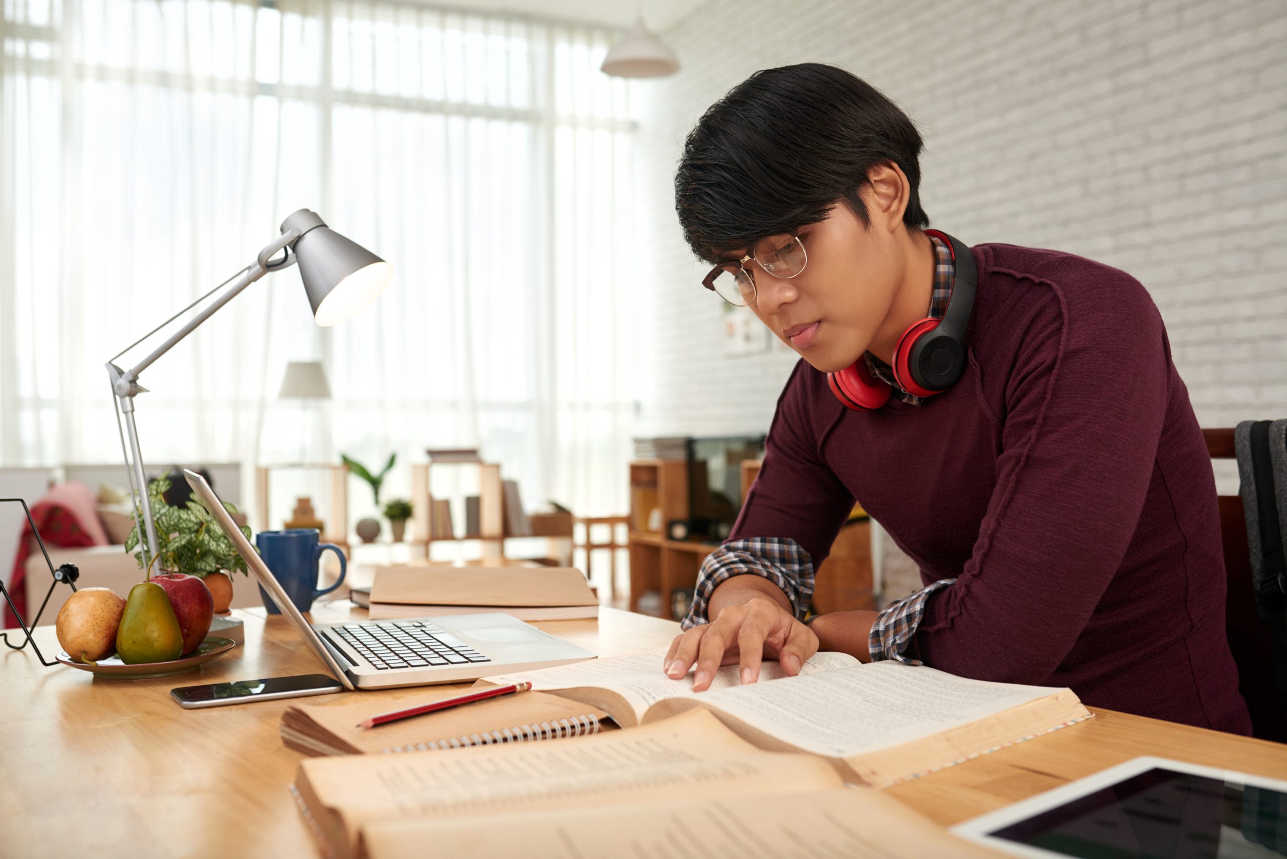 revising material Smart Asian college student preparing for exam at home